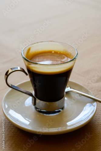 Small glass cup of black arabica coffee served in cafe, close up