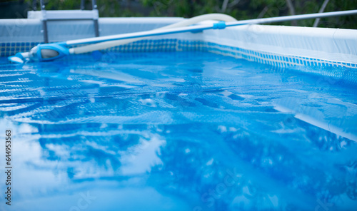 Swimming Pool with vacuum cleaner cleaning Tool. Solar film covers the pool.