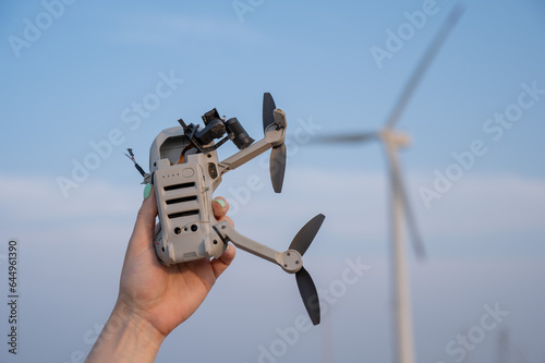 Woman holding a crashed drone against the backdrop of windmills. 