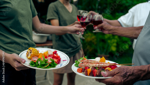 Home Garden BBQ Party, Wine Glasses Clink in Family Toast, enjoying harvest time together outside at front of house, grandfather and grandfather asian people, man and woman