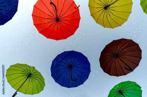 many colorful umbrellas fly and hover on the city street