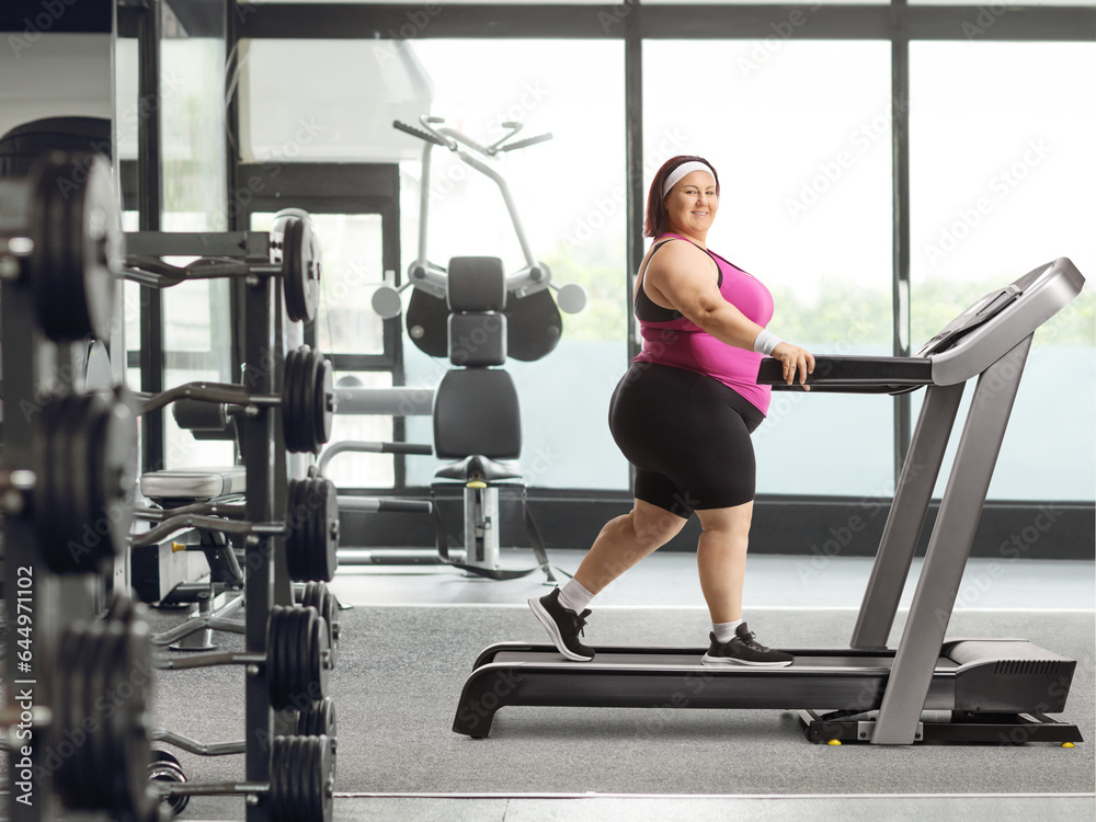Smiling young overweight woman walking on a treadmill Smiling young overweight woman walking on a treadmill