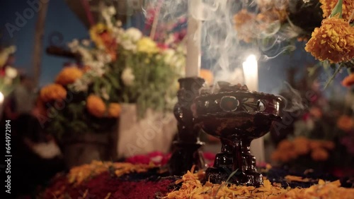 A copal goblet is burning on a grave during day of the dead celebration.