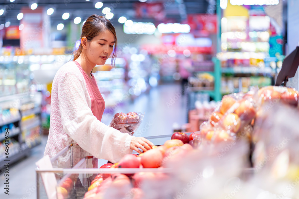Asian woman who is four months pregnant. Choosing food meticulously in the supermarket