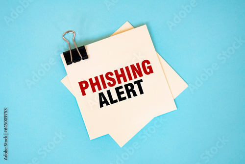 Text PHISHING ALERT on sticky notes with copy space and paper clip isolated on red background.Finance and economics concept.