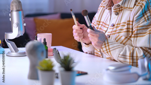 A senior woman is talking about makeup brushes during her beauty blog's live streaming