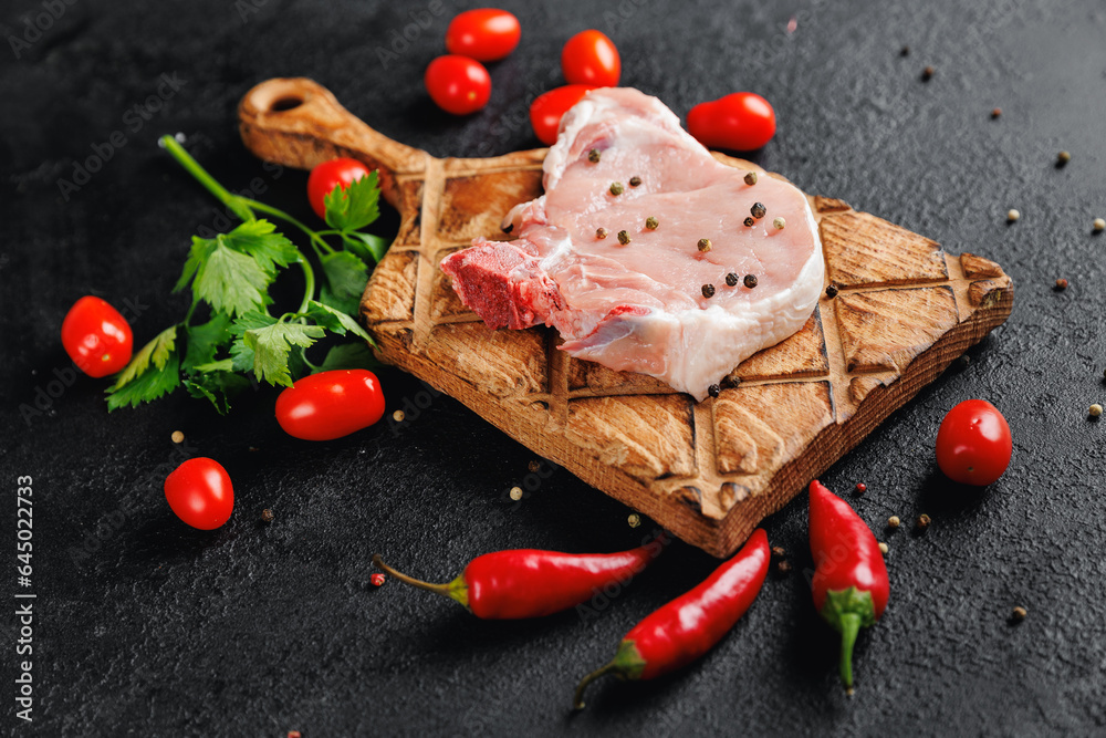 Fresh and raw meat pork entrecote steak on wooden board on dark background, top view Fresh and raw meat pork entrecote steak on wooden board on dark background, top view