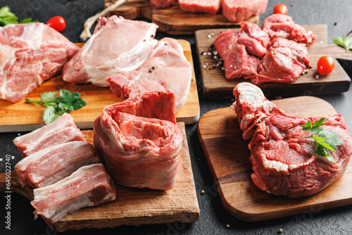 Raw fresh meat pork ribs, set beef on wooden board, top view on dark background