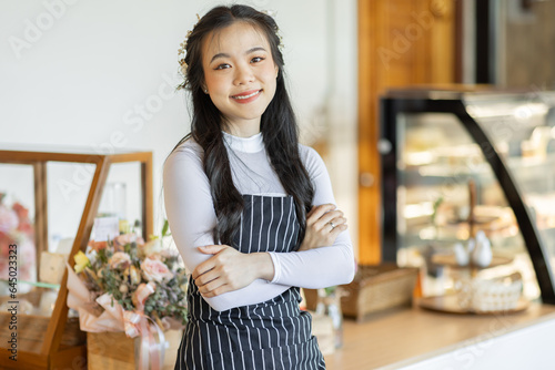 Stop by for homemade delicious bread! Portrait of asian young entrepreneur woman embracing work in her the bakery small business waiter standing in front of bakery shop.