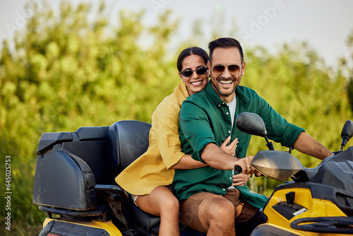 A close-up portrait of a couple in love enjoying a quad bike in nature.