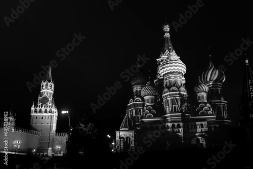 The black and white photo of the Spasskaya Tower of Moscow Kremlin and Saint Basil's Cathedral on Red Square in Russia. photo
