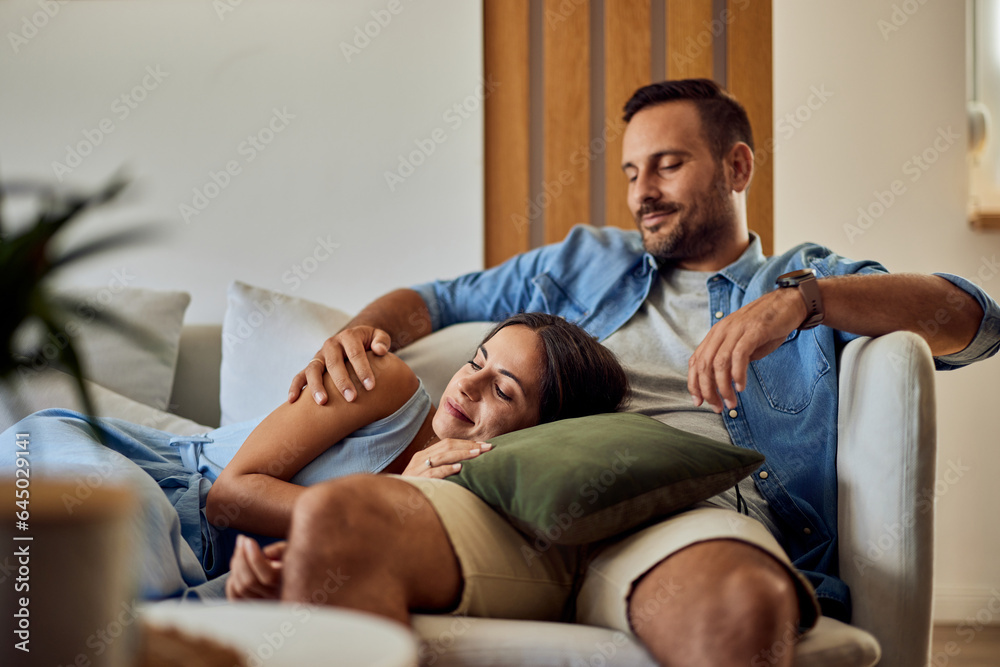 Obraz premium A pretty woman sleeping on her boyfriend's lap on the couch at home.