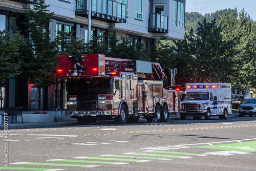 fire truck ladder co company and ambulance with flashing lights at emergency near downtown apartment building