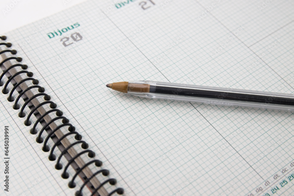 Close-up of a pen on an agenda in Catalan with the 20th and 21st on empty pages Close-up of a pen on an agenda in Catalan with the 20th and 21st on empty pages