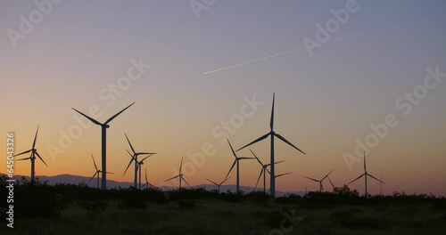 Wind turbines, windmills spinning in a field at sunset