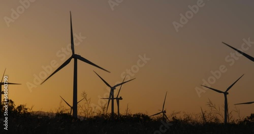 Wind turbines, windmills spinning in a field at sunset