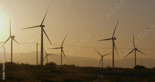 Wind turbines, windmills spinning in a field at sunset
