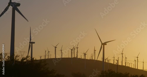 Wind turbines, windmills spinning in a field at sunset