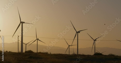 Wind turbines, windmills spinning in a field at sunset