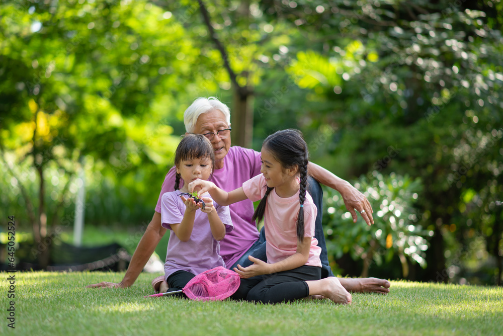 Happy Asian family children having fun and catches a net of insects with her grandfather in the park Happy Asian family children having fun and catches a net of insects with her grandfather in the park
