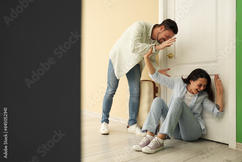 Angry husband fighting with his wife near door. Domestic violence concept