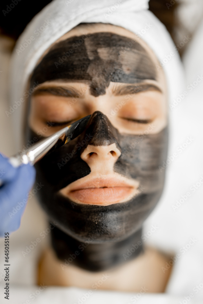 Applying carbon mask with a brush to a woman's face, preparing for a laser carbon peeling in beauty salon, close-up. Face care concept and beauty procedures Applying carbon mask with a brush to a woman's face, preparing for a laser carbon peeling in beauty salon, close-up. Face care concept and beauty procedures