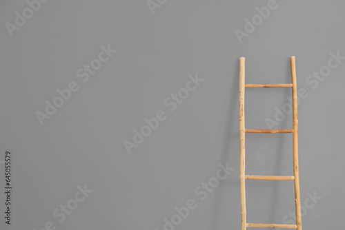 Wooden ladder near grey wall in room