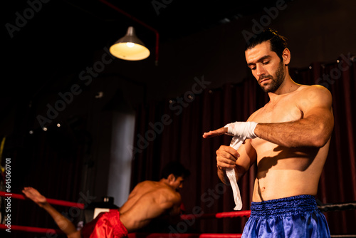 Caucasian boxer portrait with muscular and athletic body wrapping his hand or fist on the ring be fore the boxing fight match or training. Impetus