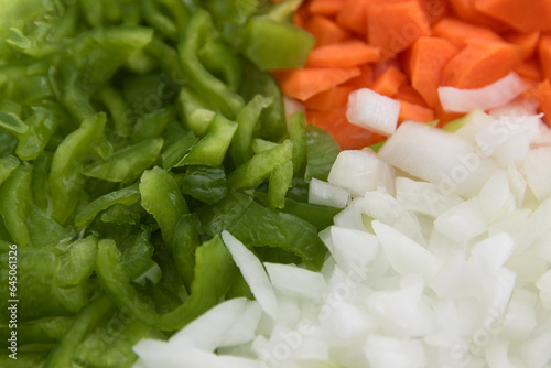Plate of chopped and chopped vegetables with green pepper, carrot, white onion