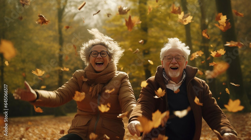 Active seniors having fun and playing with the leaves in autumn forest. Healthy and active elderly couple. Happy couple on retirement, healthy and active lifestyle.