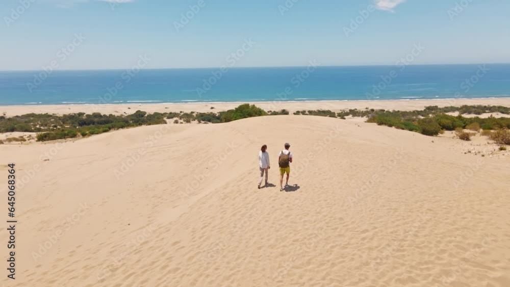 couple travelers tourists walking sandy dunes on beautiful Patara Beach on Mediterranean sea coastline. stunning desert with dunes, mountain ridge and blue sea. beautiful popular spot in Turkey