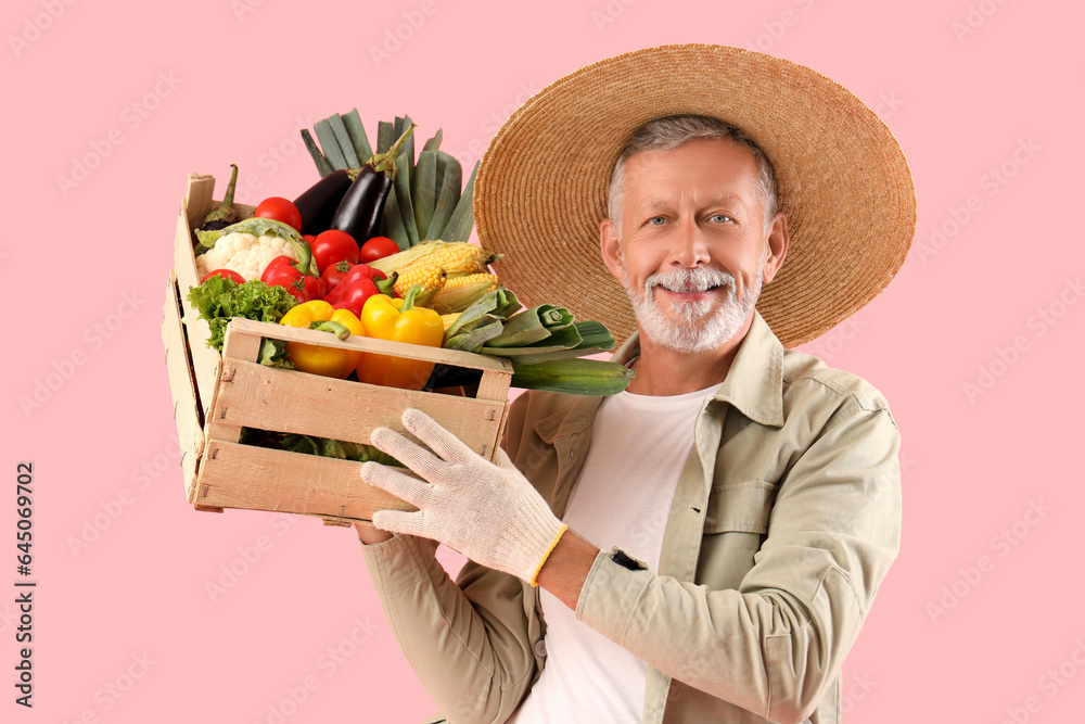 Φωτογραφία Happy mature male farmer with wooden box full of different ripe vegetables on pi