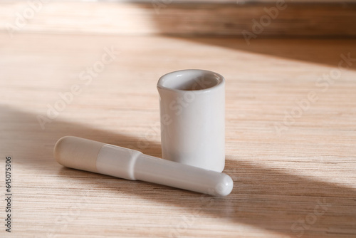 White porcelain kitchen mortar and pestle on the table on a sunny day