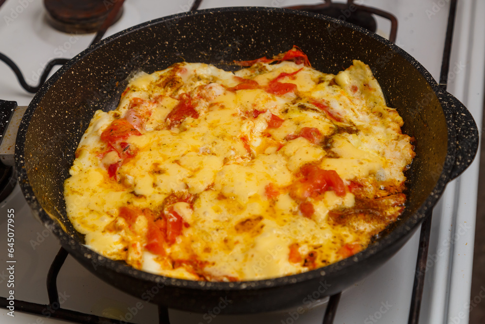 Shakshuka with tomatoes and sweet cheese sprinkled in a frying pan on the stove Shakshuka with tomatoes and sweet cheese sprinkled in a frying pan on the stove