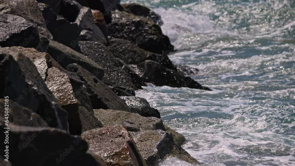 View of water splashing on the rocks as small waves roll in at the ocean. View of water splashing on the rocks as small waves roll in at the ocean.