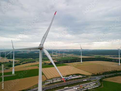 An aerial view of windmills in a field spinning under the influence of the wind and producing renewable energy in an environmentally friendly way.