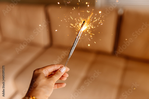 New Year and Christmas background. Bengal lights are lit, close-up hands of girls with beautiful manicure light candles