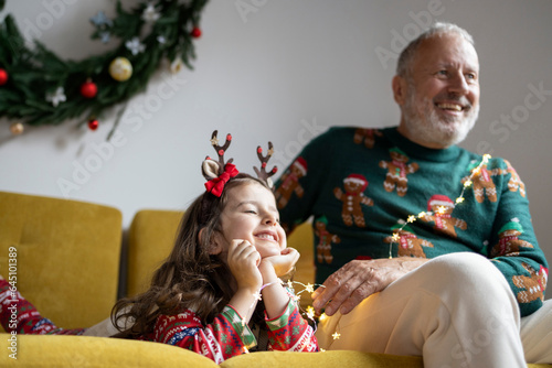 Grey haired mature father and a little cute daughter in Christmas sweater having fun and celebrating Christmas at home 