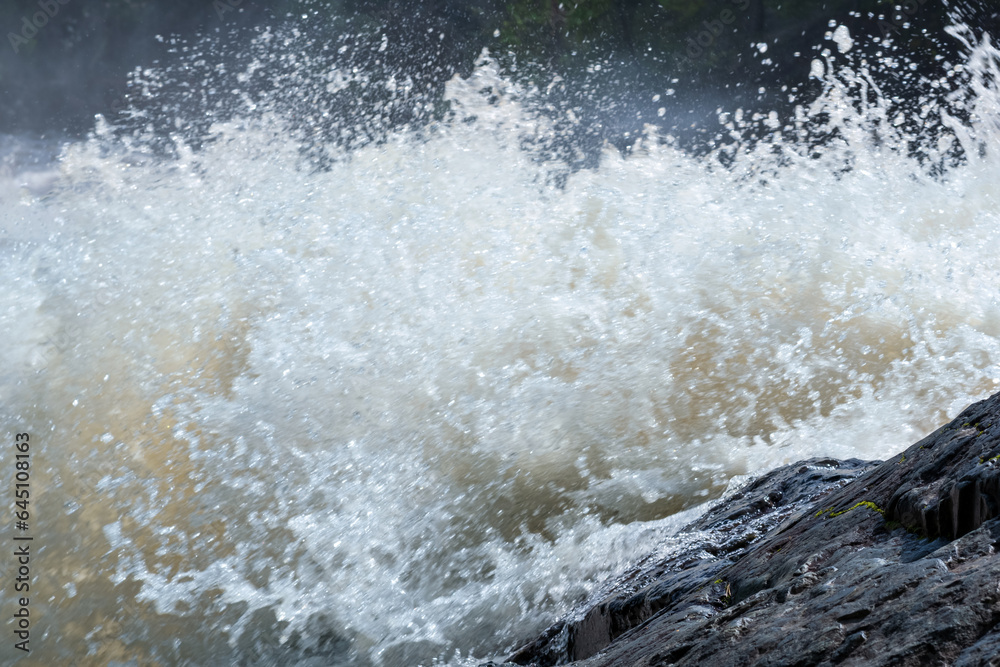 muddy turbulent stream under a rock during high water