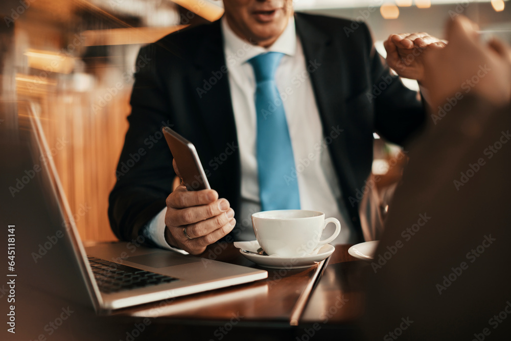 Middle aged businessman using a smartphone while drinking coffee in a cafe