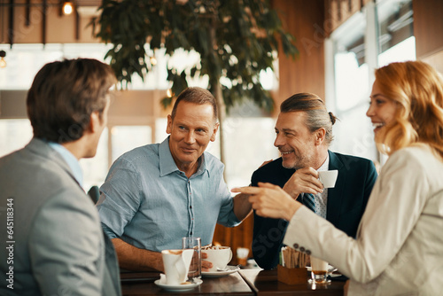 Group of middle aged business coworkers having a meeting over coffee in a cafe decorated for christmas and the new year holidays