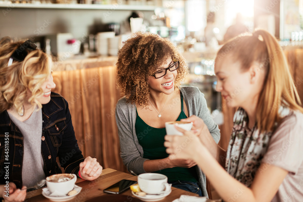 Young and diverse group of female friends enjoying coffee in a cafe