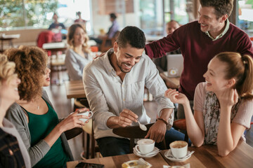 Young and diverse group of people talking while having coffee together in a cafe