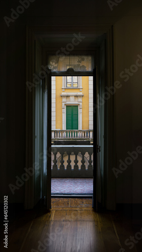 The balcony of an Italian house. Vertical wallpaper in retro style with yellow and green colors. Wooden parquet texture. Natural light in the room. Aesthetic and symmetrical vintage photography.