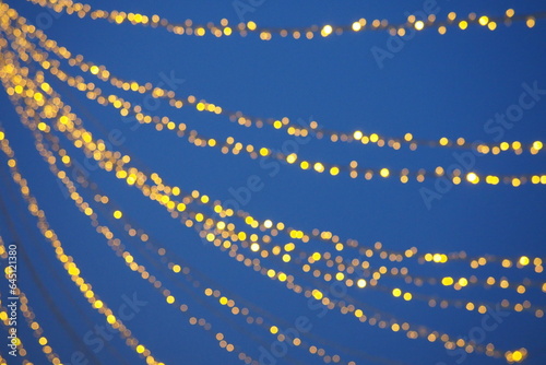 Yellow garlands against the evening sky. Defocused bokeh. New Year's and Christmas.