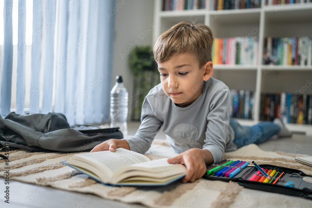 caucasian boy pupil student read book at home on the floor study learn caucasian boy pupil student read book at home on the floor study learn