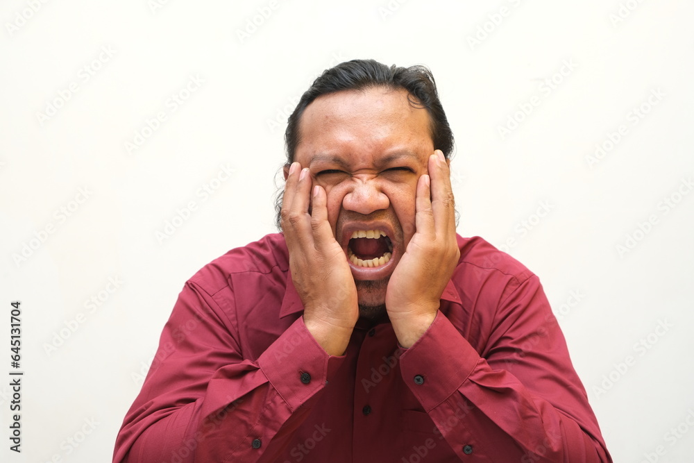 Adult Asian man touching his jaw with pain expression Adult Asian man touching his jaw with pain expression