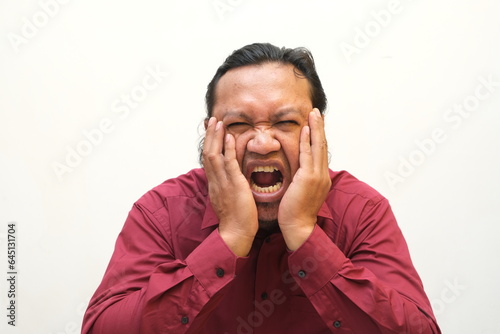 Adult Asian man touching his jaw with pain expression photo