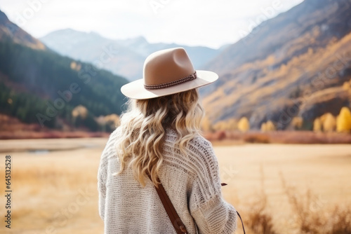 woman traveler with backpack in hat and looking at mountains and forest. hobby, recreation, hiking and tourism