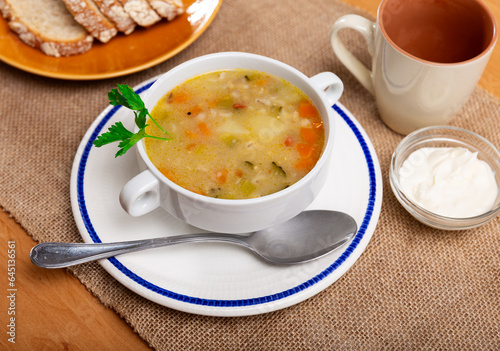 Popular dish of Russian cuisine is pickle soup with meat, cooked on basis of pickled cucumbers and pearl barley or rice, decorated with sprig of parsley on top